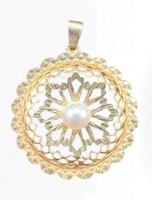 a close up of a gold pendant with a pearl in the center