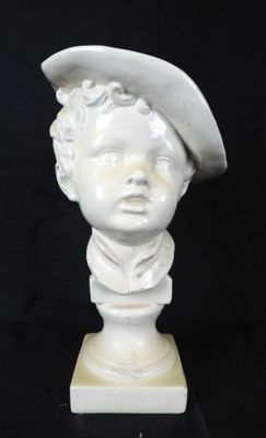 buste en marbre blanc représentant un garçon coiffé d'un chapeau, posé sur un socle en marbre