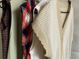 three sweaters hanging on a rack in front of a wall