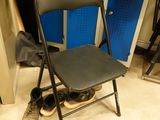 a black folding chair in a room with blue lockers