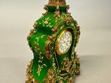a green and gold clock sitting on a white surface