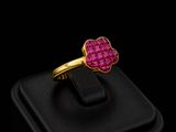 a gold ring with pink stones on a black surface