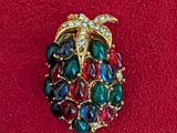 an image of a brooch with multi colored stones on a red surface