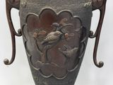 a large metal vase with a bird and flower design on it