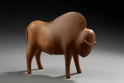 une petite sculpture en bois représentant un taureau sur une surface grise