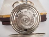 a silver pocket watch sitting on top of a book
