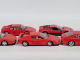 six red toy cars are lined up in a row on a white surface