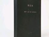 an old book with a black cover sitting on top of a white table