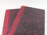 deux cahiers rouges posés l'un sur l'autre sur une surface blanche