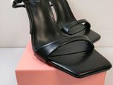 un gros plan sur une paire de chaussures noires posées sur une boîte rose