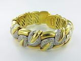 a close up of a gold and diamond bracelet on a white surface