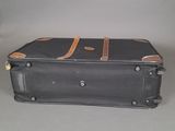 a black suitcase sitting on a table with a brown handle