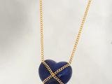 un collier en forme de cœur bleu avec une chaîne dorée sur fond blanc