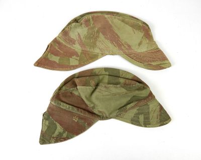 une paire de casquettes militaires ornées d'un motif camouflage sur fond blanc