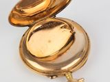 an image of a gold pocket watch with a key on a white surface