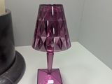 a purple table lamp on a white table next to a black vase