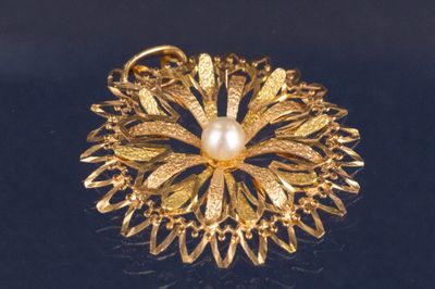 une broche en or ornée d'une perle au centre