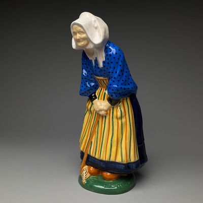 figurine of a woman in a blue dress and yellow skirt holding a cane