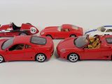 four toy cars are lined up in a row on a white surface