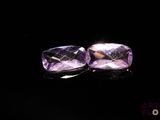 two purple amethtites on a black surface with a black background
