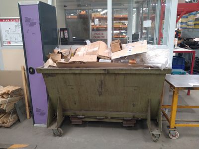 une benne à ordures au milieu d'une pièce remplie de cartons
