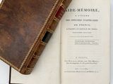 an old book sitting on top of an open book on a table
