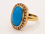 a close up of a gold ring with a blue stone surrounded by diamonds
