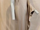 une photo d'un mannequin vêtu d'une robe beige, posé sur un socle