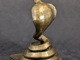 brass sculpture of a bird on a pedestal on a gray background