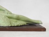 a statue of a woman laying down on a wooden base