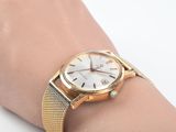 a woman ' s wrist that has a gold watch on it