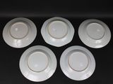 four white plates with white rims are sitting on a black surface