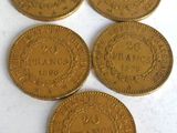 five gold coins sitting on top of each other on a white surface