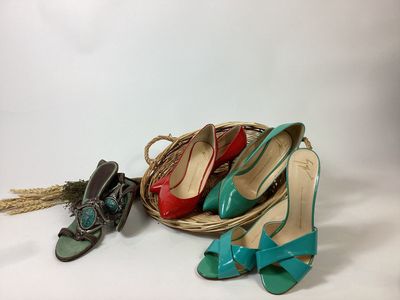 several pairs of women ' s shoes and a basket on a white surface