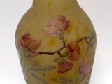 a yellow vase with pink flowers on it on a white surface