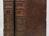 two old books sitting on top of each other on a white surface