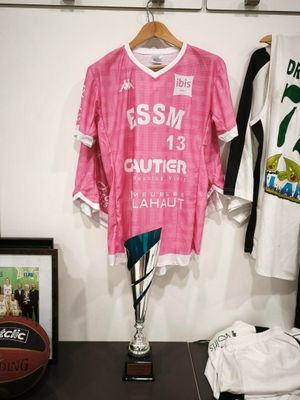 une chemise rose accrochée au mur à côté d'un ballon de basket