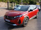 La voiture rouge est garée sur le parking, à côté d'autres voitures.
