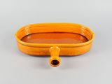 an orange bowl with a pipe sticking out of it on a gray surface