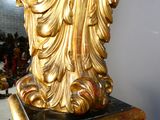 a gold statue on a black pedestal in a room