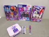three barbie dolls and a tin of pencils on the table