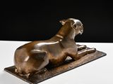 bronze sculpture of a dog laying down on a white surface