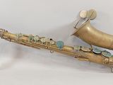 un vieux saxophone en laiton muni de boutons, posé sur une surface blanche