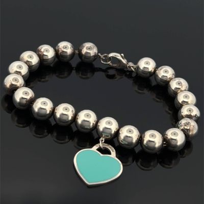 a bracelet with a heart charm on a black surface