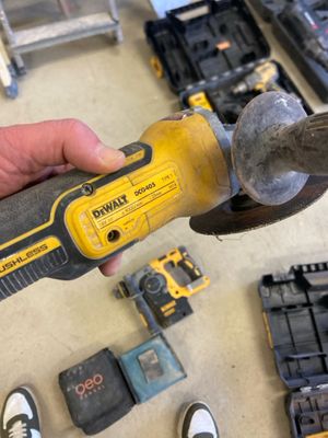 a person holding a hammer in their hand with other tools on the table