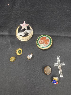 Plusieurs épingles et une croix sont posées sur un tissu noir.