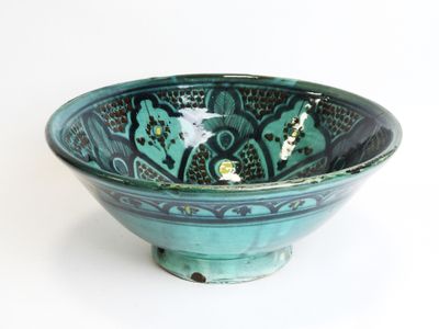 a green bowl with a design on it on a white surface