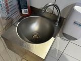 a sink in the corner of a bathroom with a soap dispenser