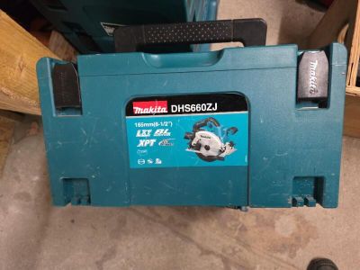 La perceuse Makita est posée par terre à côté d'une boîte à outils.