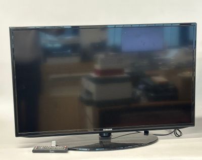 a flat screen tv sitting on a table next to a remote control